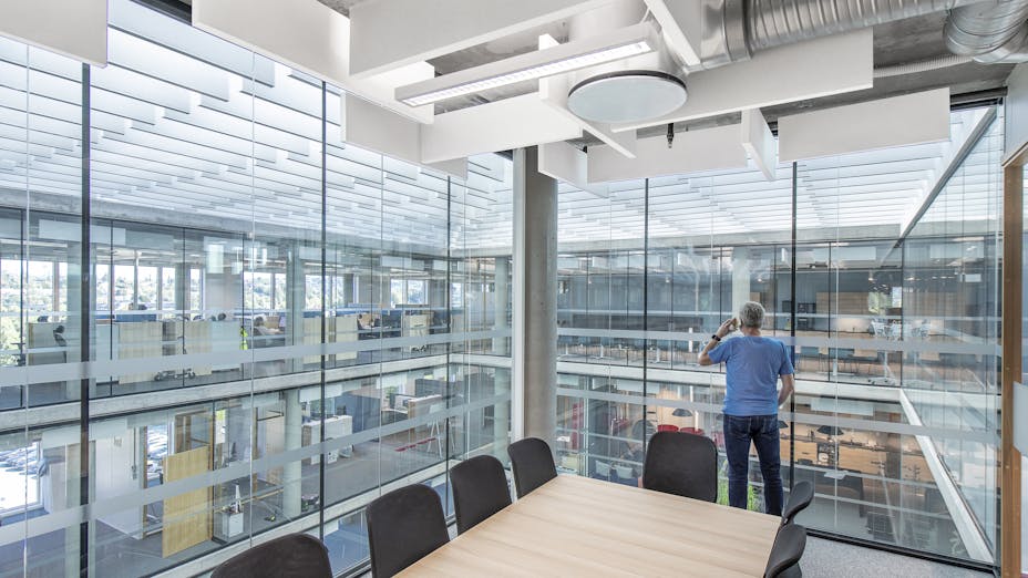Man in office looking out over the rest of the building