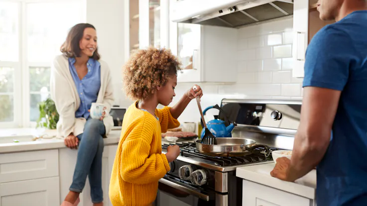 Close up of young family spending time together while preparing food in their kitchen, selective focus