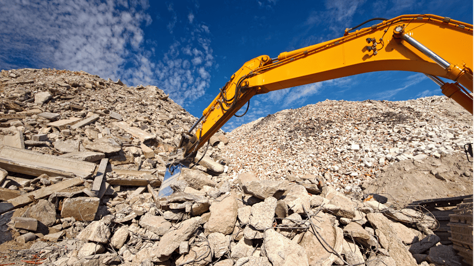Excavator digging through demolished building