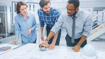 People in office standing around a table, discussing, planning. Stock image.