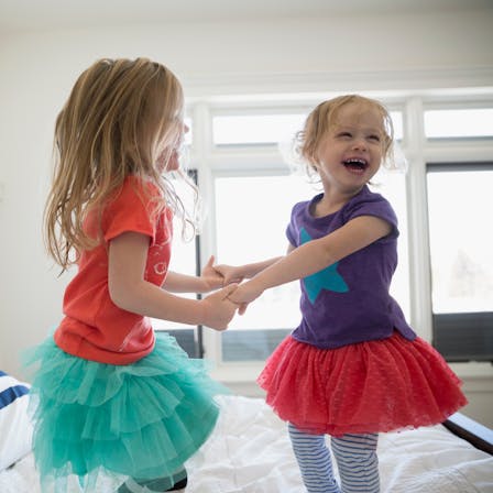 Playful sisters holding hands and jumping on bed. People, children, indoor, acoustics