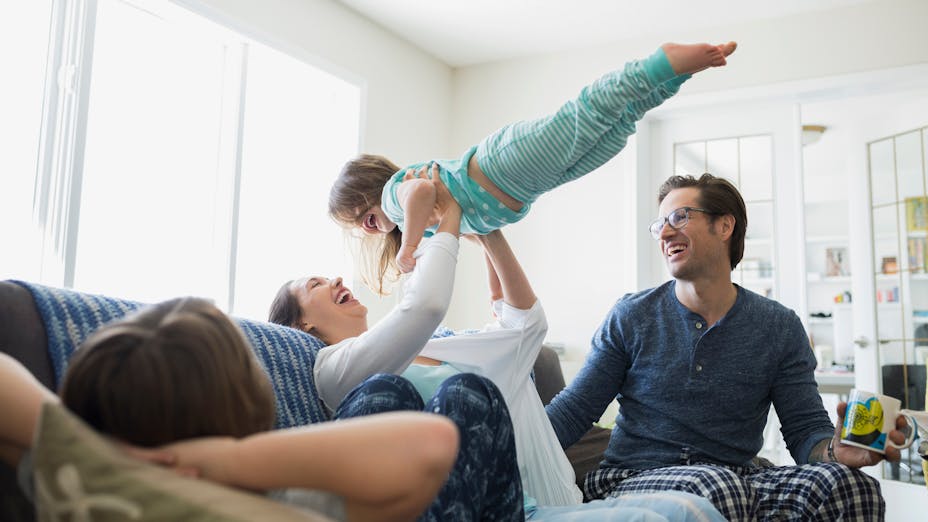 People indoor living room
Playful mother lifting daughter overhead on sofa