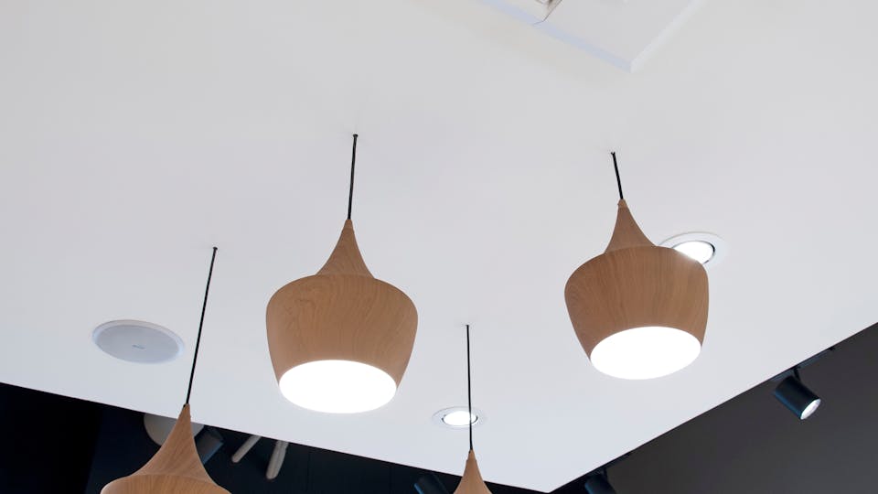 Wooden pendant lighting integrated seamlessly into an acoustic island from Rockfon