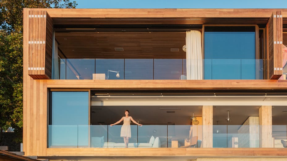 Woman standing on hear balcony of her wooden house