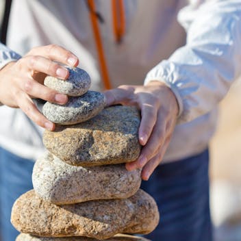 Young person stacking stones at the beach