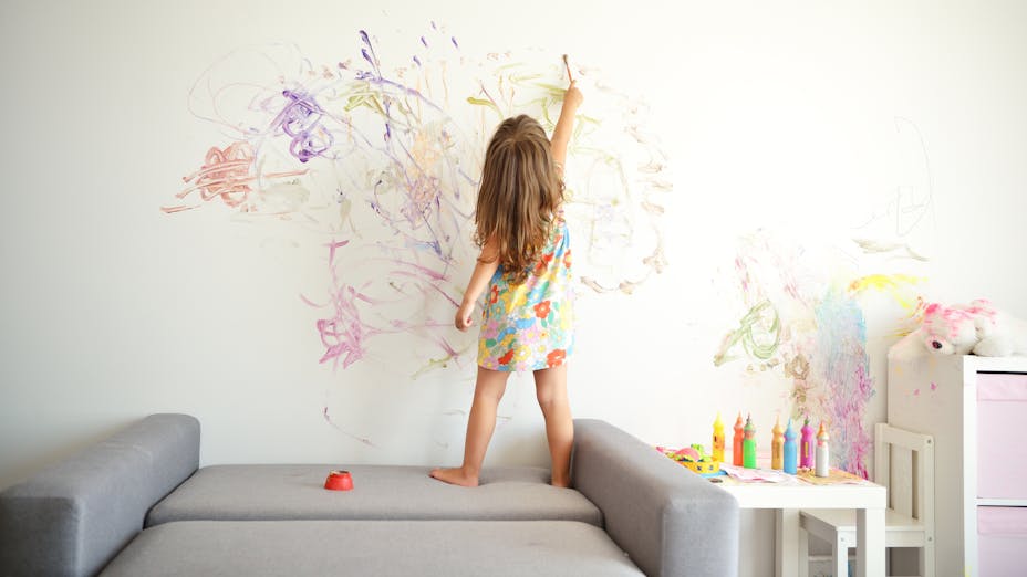 a child happily drawing different colours on her wall