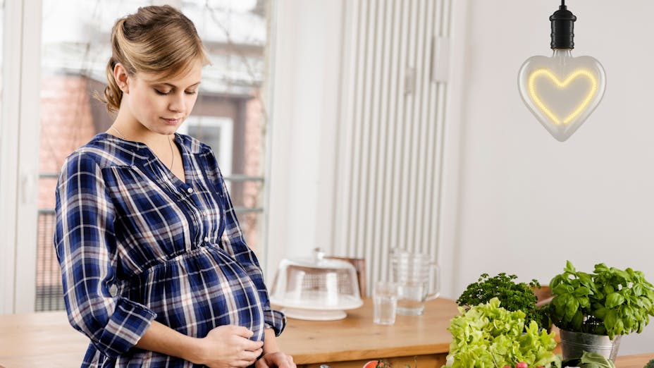Femme enceinte prépare des aliments frais dans la cuisine