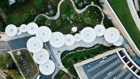 Aerial view of a modern house and garden complex with multiple round umbrella like ceilings creating an intriguing visual