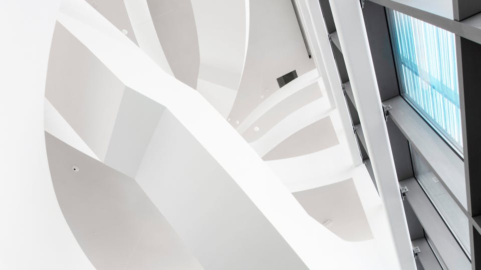 Unique staircase stretching the entire height of the building is a matt white seamless acoustic wall and ceiling system