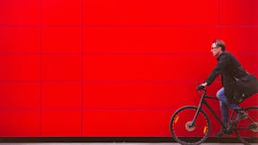 Man riding bicycle in front for red wall
iStock-627884444; Used for cover of Sustainability Report 2018. 

Vibrant Color; Real People; Travel; Male; Traveling; Businessman; Men; City Life; Commuter; Healthy Lifestyle; Caucasian Ethnicity; Business Travel; One Person; Vitality; On The Move; Red; Modern; Urban Scene; Outdoors; Horizontal; Cycling; Street; Bicycle;  Riding; Bike