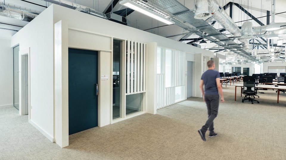 Open plan office, utilitarian design with exposed services, a seamless acoustic ceiling above