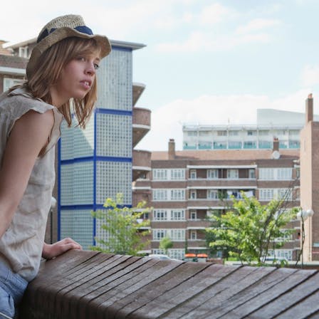 Woman on rooftop looking at the surroundings. Balcony. High-rise. Apartments. Flats.
