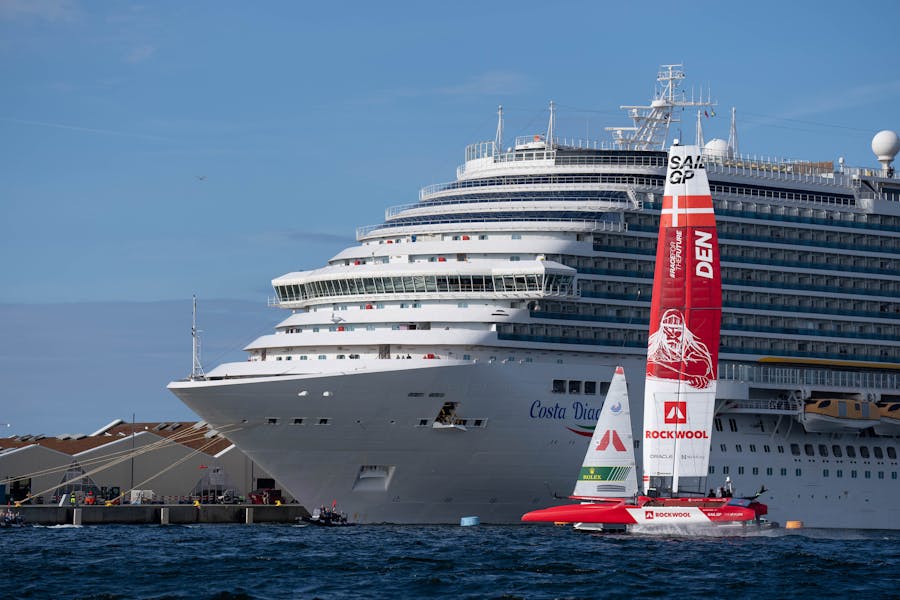 The Denmark SailGP Team's F50 in Copenhagen sailing next to a cruise ship. The wing shown is the medium-sized wing with a height of 24m.
