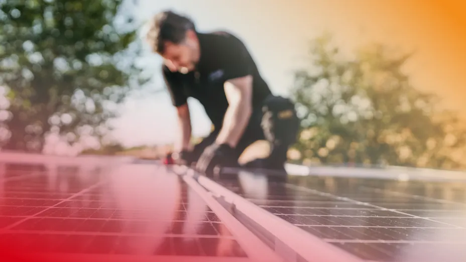 Ein Experte installiert eine Photovoltaik-Anlage auf einem mit ROCKWOOL gedämmten Dach.