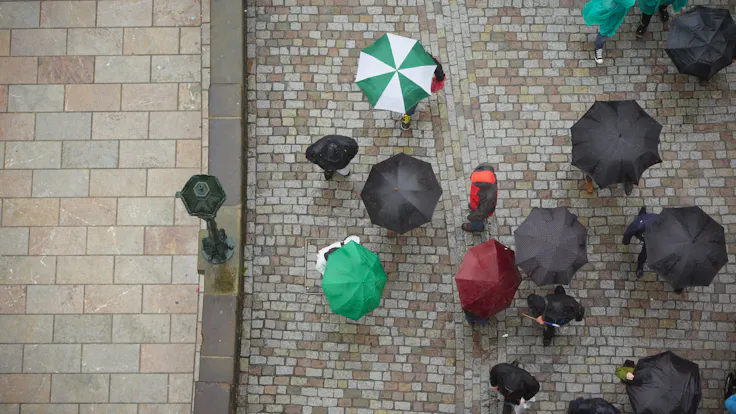 Birds-eye view, umbrellas in street, rain. Photo used first in the Sustainability Report 2017