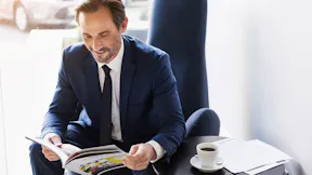 Joyful man in suit entertaining with journal in cafe